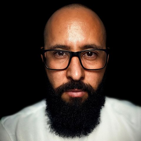 Edilberto Venção, autor do livro, de óculos e barba, olhando para a câmera.